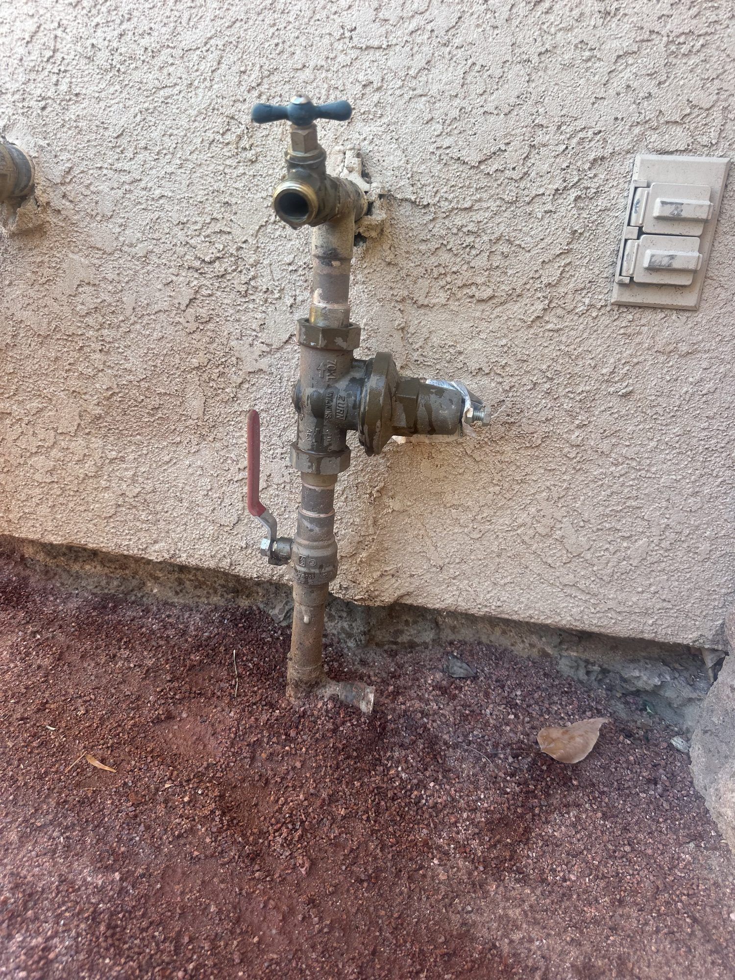 New brass water pressure regulator and hose bib installed on the outside wall